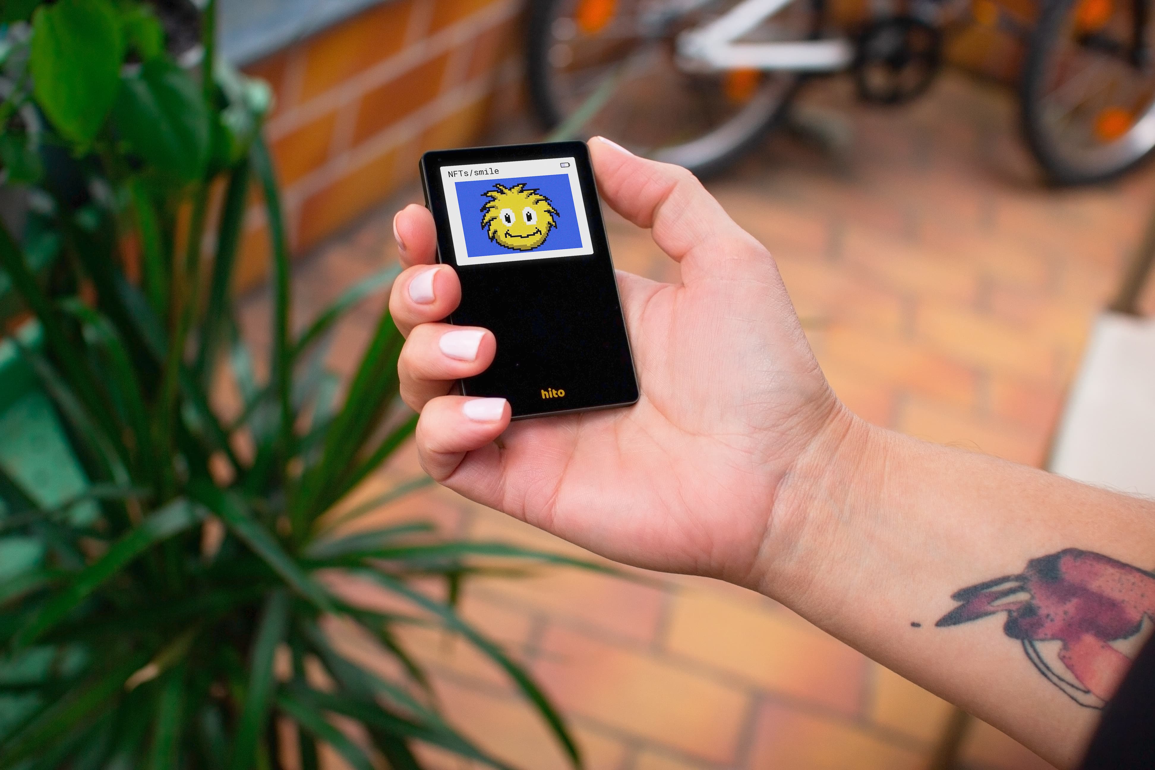 Hito hardware wallet held in one hand, with its touchscreen and glass finish clearly visible